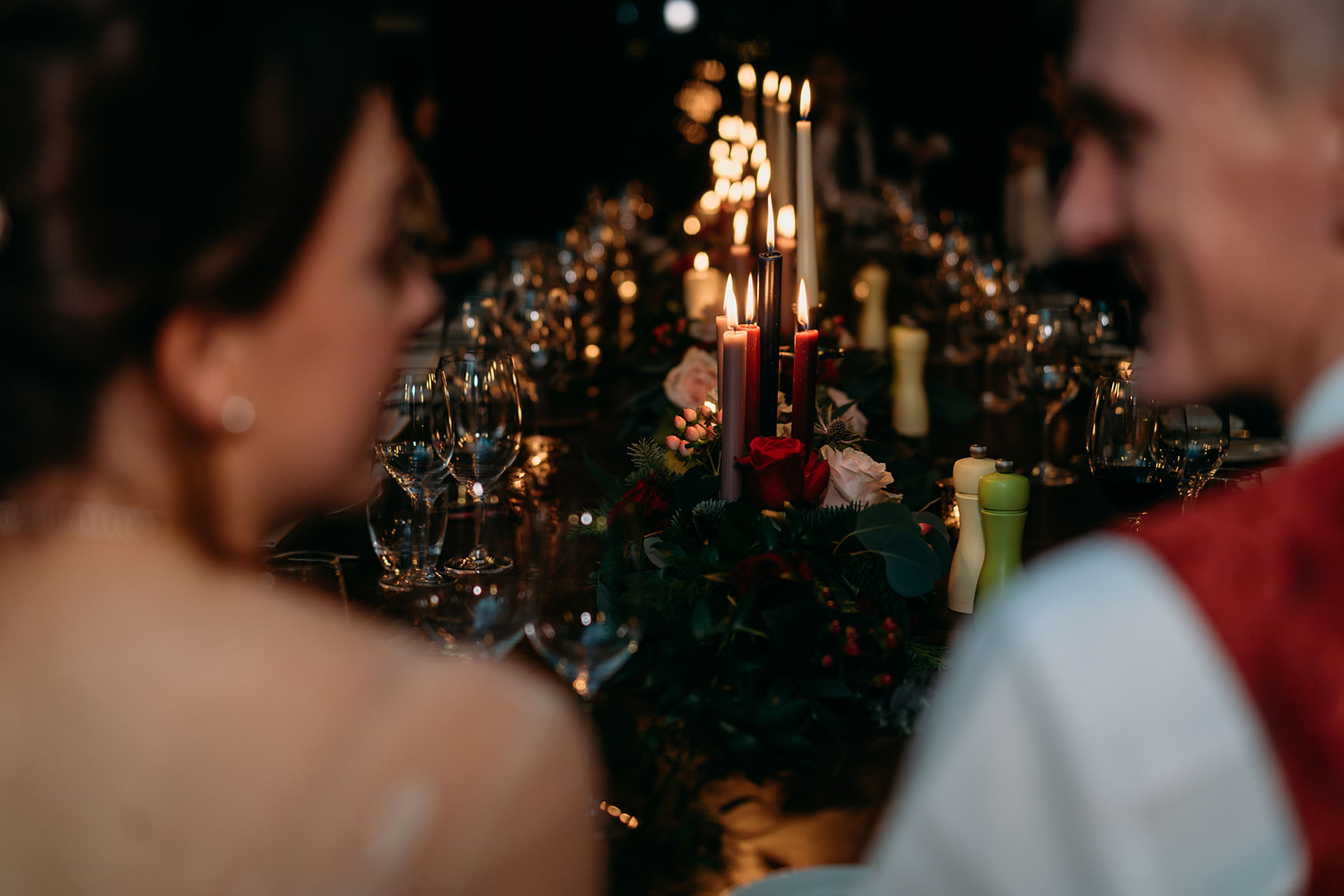 couple look at each other over candlelit dinner - airbnb wedding advice