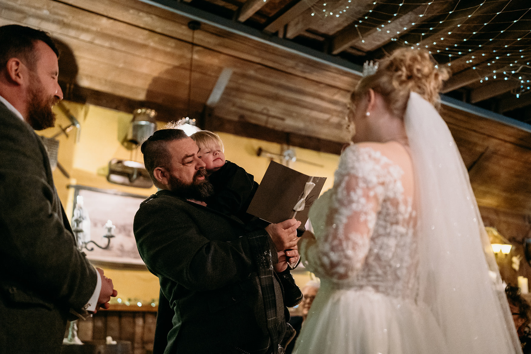 Groom says vows as his son sleeps on him during The Gathering at Woodhead Farm wedding ceremony